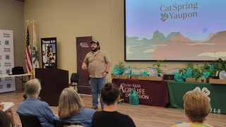 Man giving a presentation at an event with 'CatSpring Yaupon' 