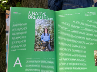 Person holding an open book with green pages and a photo of a woman on a tree-lined path.