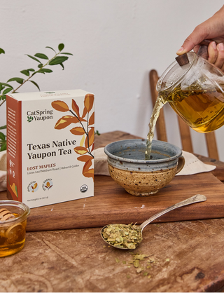 Person pouring tea into a bowl with a box of Texas Native Yaupon Tea in the background.